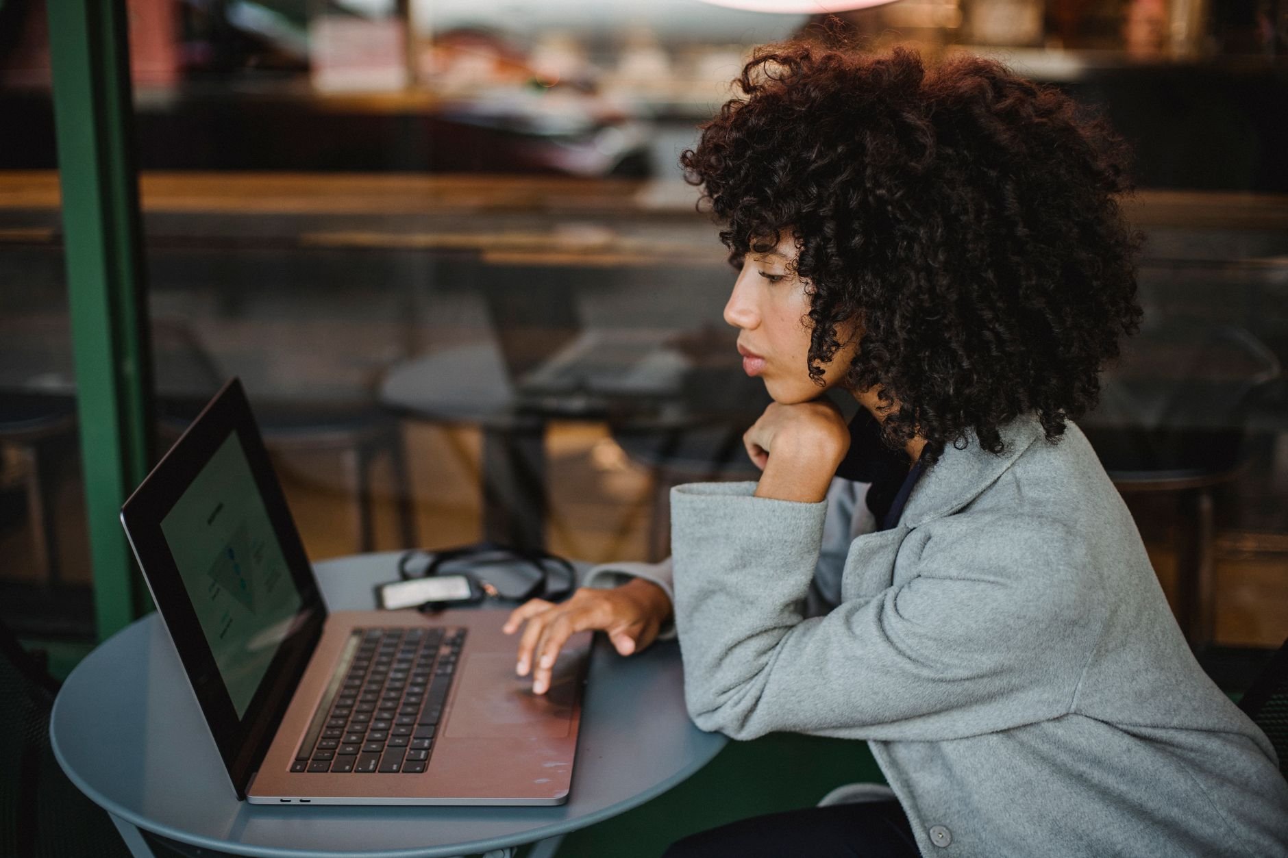 Young woman focused on her laptop while working at a cosy coffee shop.